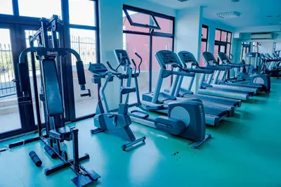 a gym with rows of tread machines and windows at Menada Apartments in Marina Cape in Aheloy