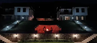 a couple standing in front of a house at night at Eco Lodge St Ignatius Еко лодж Игнажден in Debelets