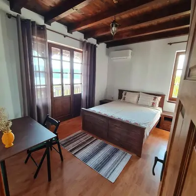a bedroom with a bed and a table and windows at Eco Lodge St Ignatius Еко лодж Игнажден in Debelets