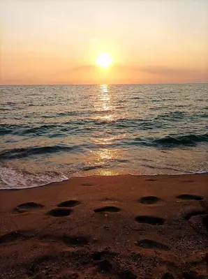 a sunset on the beach with footprints in the sand at Sea Time Sozopol in Sozopol