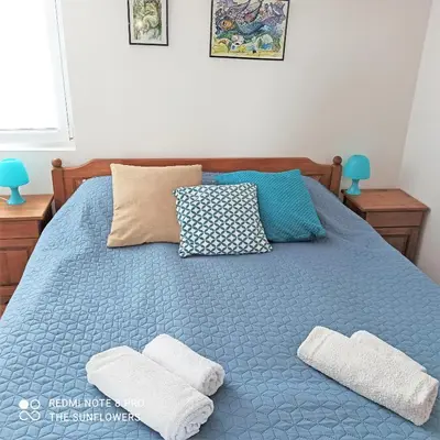 a blue bed with two white towels on it at Guest House Sunflowers in Pomorie