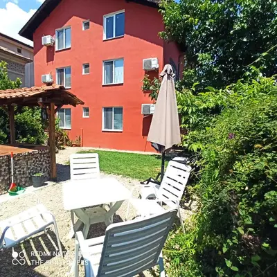 a table and chairs and an umbrella in front of a building at Guest House Sunflowers in Pomorie