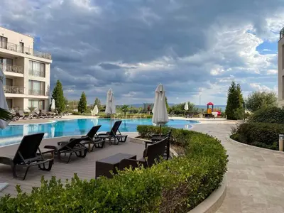 a pool with chairs and umbrellas next to a building at Diamond Beach Apartment 2 Room in Burgas City