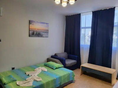 a bedroom with a bed and a chair and a window at Complex ELIT Cacao Beach - Apartments for rent- ЕЛИТ Слънчев бряг in Sunny Beach
