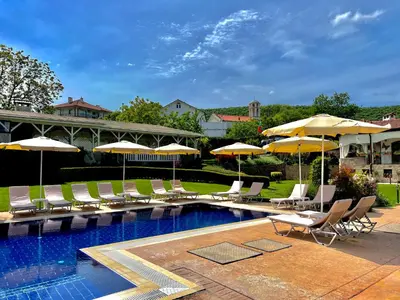 a swimming pool with lounge chairs and umbrellas at Guest House PETRA- Medovo, Sunny beach in Razvalini Balchikioy