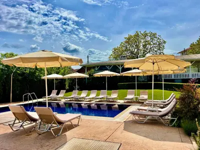 a swimming pool with chairs and umbrellas next to a pool at Guest House PETRA- Medovo, Sunny beach in Razvalini Balchikioy
