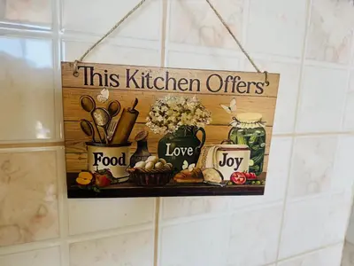 a sign hanging on a wall with a shelf with kitchen items at Kiwi Gardens in Byala
