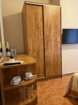a room with a wooden cabinet with cups and saucers at Хотел ЮГ in Primorsko