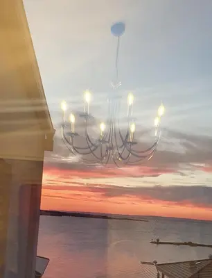 a chandelier hanging over the ocean at sunset at Апартамент Злато изглед МОРЕ in Sozopol