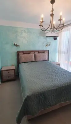 a bedroom with a bed and a chandelier at Апартамент Злато изглед МОРЕ in Sozopol