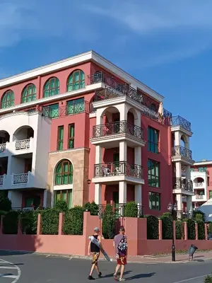 two people walking in front of a pink building at Rooftop Sea View Apartment Sveti Vlas in Sveti Vlas