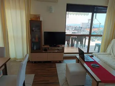 a living room with a television and a table with a laptop at Rooftop Sea View Apartment Sveti Vlas in Sveti Vlas