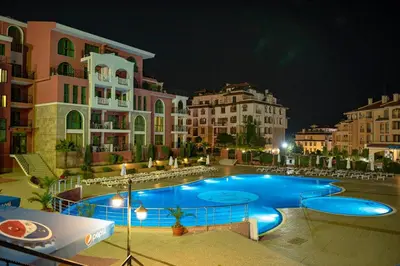 a large swimming pool in front of some buildings at night at Rooftop Sea View Apartment Sveti Vlas in Sveti Vlas
