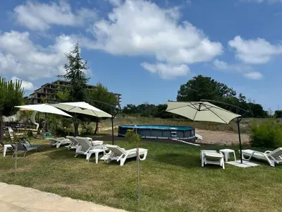 a group of white chairs and umbrellas on a field at Hotel Surf Primorsko in Primorsko