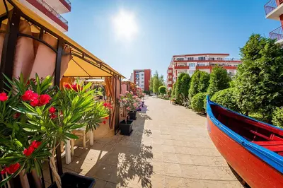 a boat on a sidewalk next to a building with flowers at Paradise View in Sunny Beach