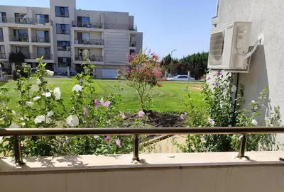 a balcony with flowers and a yard with a building at Sarafovo Sea Paradise in Burgas City