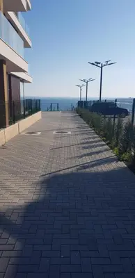 an empty sidewalk next to a building and the ocean at Сарафово Лукс Тераса Първа Линия in Sarafovo