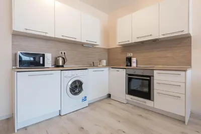 a kitchen with white cabinets and a washer and dryer at Seaside Apartment in Varna City