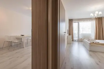 a white room with a bed and a dining room at Seaside Apartment in Varna City