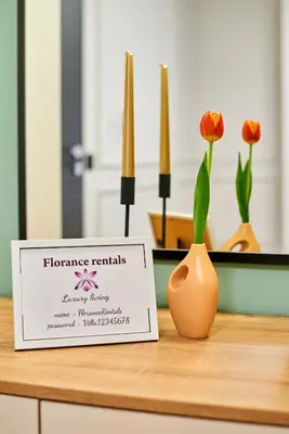 a sign on a table with a vase and flowers at Florance Rentals Luxury Apartments in Burgas in Burgas City