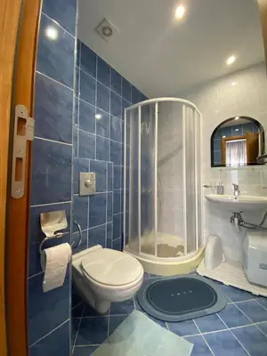 a blue tiled bathroom with a toilet and a shower at YS Residence in Sunny Beach