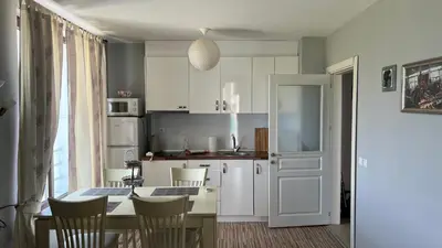 a kitchen with a table and chairs and a kitchen with white cabinets at Stamopolulux директен изглед към морето in Primorsko
