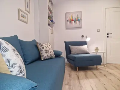 a living room with a blue couch and a chair at Apartment Marbél - Designer Retreat with FREE parking in Burgas City