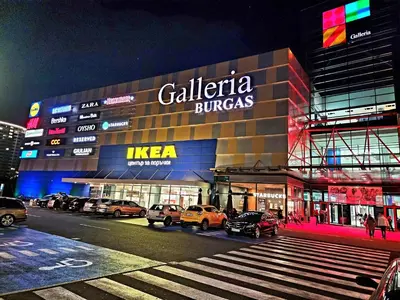 a building with cars parked in front of it at night at Central Park Galleria in Burgas City