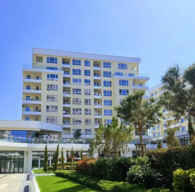 a large white building with palm trees in front of it at Central Park Galleria in Burgas City