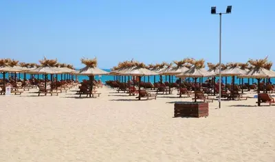 a beach with chairs and umbrellas on the sand at Студия Sunset Beach Солнечный Берег in Sunny Beach
