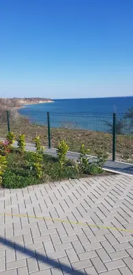 a walkway near the ocean with a fence and flowers at Сарафово Лукс Гарден Първа Линия in Burgas City