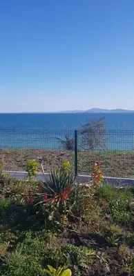 a fence with flowers in front of the ocean at Сарафово Лукс Гарден Първа Линия in Burgas City