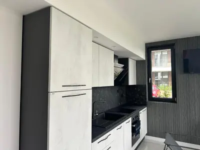 a kitchen with white cabinets and a sink and a window at Сарафово Лукс Гарден Първа Линия in Burgas City