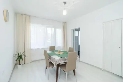 a white dining room with a table and chairs at Римски Терми Варна in Varna City