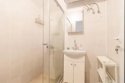 a white bathroom with a sink and a shower at Римски Терми Варна in Varna City