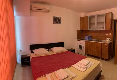 a bedroom with a bed with a red comforter at Stamopolu Parter in Primorsko