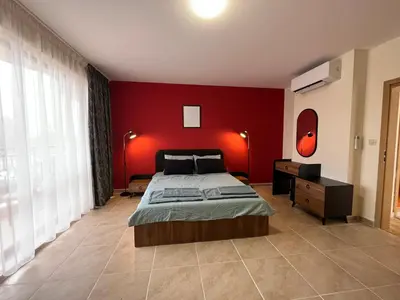 a bedroom with a red wall with a bed and a desk at River park 2 bedroom apartment in Nesebar