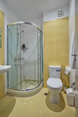 a bathroom with a toilet and a glass shower at Апартамент на плаж Градина in Chernomorets