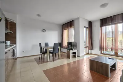 a living room with a table and chairs and a television at Апартамент на плаж Градина in Chernomorets