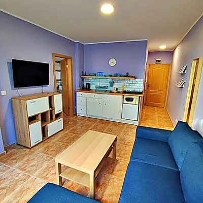 a living room with a blue couch and a tv at BRAVO 5 - Sunny Beach Center in Sunny Beach