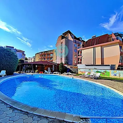 a large blue swimming pool with chairs and buildings at BRAVO 5 - Sunny Beach Center in Sunny Beach