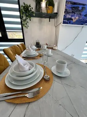 a table with white plates and cups and saucers at Marino Liberta South Beach Obzor in Obzor