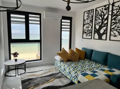 a living room with a couch and a table and windows at Marino Liberta South Beach Obzor in Obzor