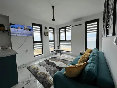 a living room with a blue couch and some windows at Marino Liberta South Beach Obzor in Obzor