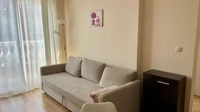 a living room with a couch in front of a window at 2 Room Apartment in Luxury Complex Sunny Beach in Sunny Beach