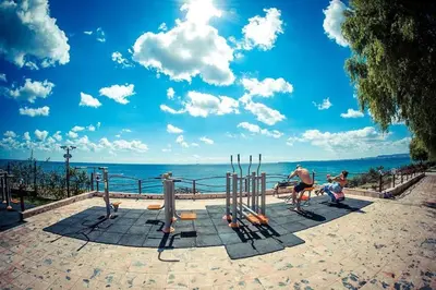 a man and two children playing in a playground with the ocean at Studio Robinson Beach Sea Nessebar View in Sveti Vlas