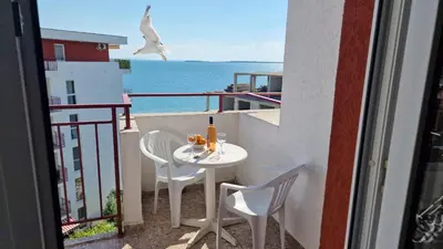 a table and chairs on a balcony with a view of the ocean at Studio Robinson Beach Sea Nessebar View in Sveti Vlas