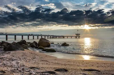a pier on the beach with the sun setting at Batak Studio in Burgas City