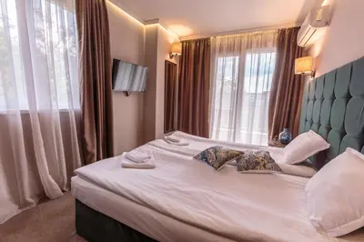 a bedroom with a white bed with a large window at Хотел МИКАДО - онлайн self check-in in Burgas City