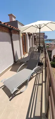 a row of chairs on a balcony with an umbrella at Модерен апартамент в сърцето на Созопол in Sozopol